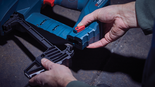 Voici la traduction :

Mains tenant un outil bleu et rouge. Le texte "BRUSHLESS" est visible. Un accessoire noir est en cours de positionnement.