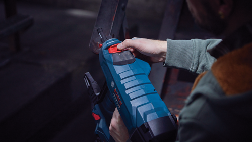 Personne tenant un outil Bosch GN818V-12 HD bleu et noir.