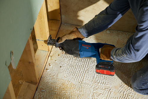 Personne utilisant une scie alternative Bosch Lithium-Ion 18V pour couper du bois, avec le texte "BOSCH" visible.