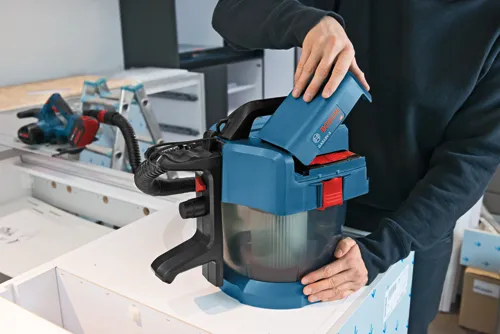 Aspirateur GAS18V-3 Bosch, avec personne tenant le couvercle supérieur.