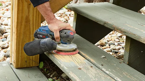 Bosch GEX18V-5, ponceuse CORE18V 4 Ah ponçant des escaliers en bois vieilli.