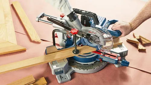 bosch cordless 18v AMPshare CORE18V miter saw on floor cutting piece of wood at an angle