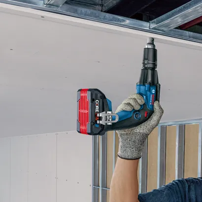 Bosch GTB18V-45, visseuse à plaques de plâtre professionnelle, tenue par une personne portant un gant, illustrée lors de l'installation de plaques de plâtre.
