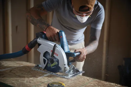 Voici la traduction :

Personne portant un équipement de protection individuelle utilisant une scie circulaire Bosch.