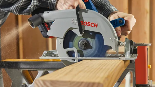Scie circulaire Bosch coupant du bois ; "BOSCH" et "18V" visibles.