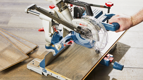 bosch cordless 18v AMPshare CORE18V miter saw on floor cutting piece of wood flooring