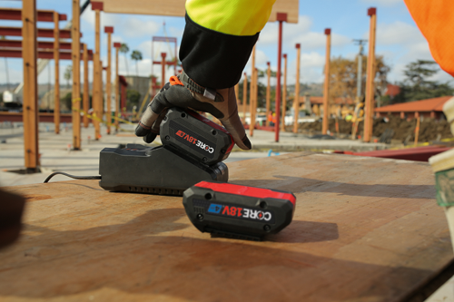 Voici la traduction :

Une main gantée place une batterie sur une station de charge, avec une autre batterie à proximité ; les batteries indiquent CORE 18V.