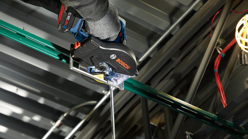 Scie circulaire Bosch, batterie CORE18V 4 Ah, coupant une pièce métallique verte, le mot 'BOSCH' est clairement visible.