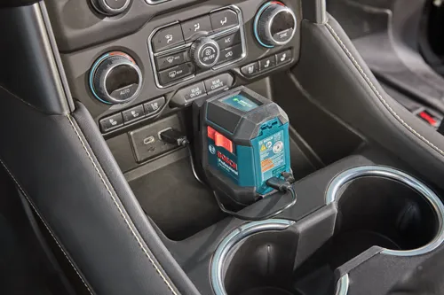 Niveau laser vert Bosch Professional GLL50-20G dans la console de la voiture, branché sur le port USB.