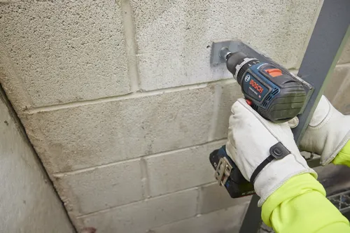 Bosch GSB18V-800C HD Perceuse sans fil sans balai perçant un mur en blocs.