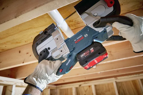 Scie circulaire Bosch GCB18V-5 coupant un tuyau blanc, avec une batterie AMP Share! 18V 6 Ah.