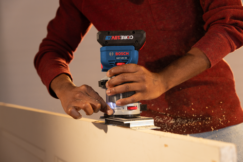 Utilisateur utilisant une défonceuse Bosch GKF18V-25 pour couper du bois.