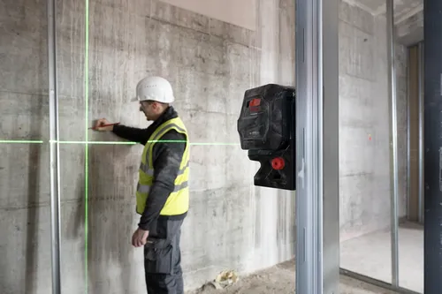 Bosch Professional GCL 2-50 CG, un ouvrier du bâtiment l'utilise pour marquer le mur avec un crayon.