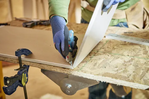 A worker using the Bosch H11-11100-1 folding knife on a wood layer.