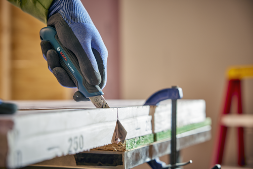 A person using the Bosch H11-12100-1 snap off knife cutting a wood material.