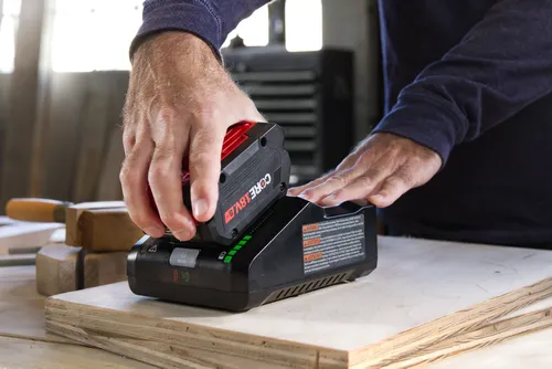 Personne insérant une batterie CORE 18V dans le chargeur ; le chargeur est doté de la technologie « ACTIVE AIR COOLING » et d’un bouton « MODE ».