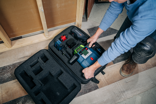 Voici la traduction :

Personne manipulant un ensemble d'outils de nivellement Bosch à l'intérieur d'une mallette, contenant divers outils et accessoires.