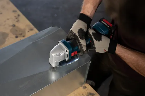 The worker using the GSC18V-16E 18V 16-Gauge Metal Shear with Lock- On Slide Switch to cutting a metal plate.