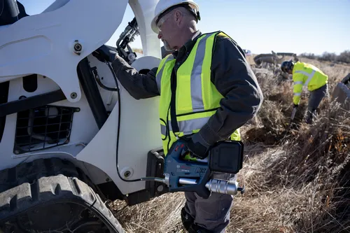 A worker using the Bosch GFP18V-10 18V Grease Gun for use in a construction vehicle.