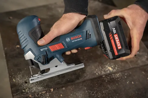 A worker attaching a Bosch EXBA18V-60 EXPERT 18V 6 Ah High Power Battery to a GST18V-50B 18V barrel-grip jig saw.