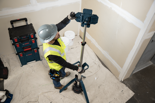 The worker using the Bosch GLT18V-5000N 18V Tower Light directed at a wall undergoing renovation for lighting purposes.