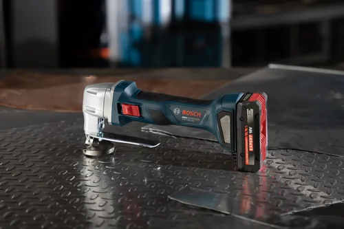 The Bosch GSC18V-16EN 18V 16-Gauge Metal Shear with Lock- On Slide Switch on a metal table with a battery.