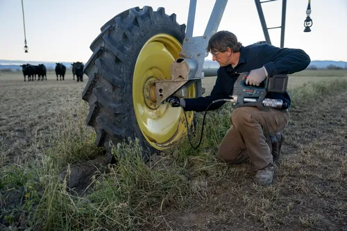 A worker using the Bosch GFP18V-10 18V Grease Gun for use on agricultural machinery.