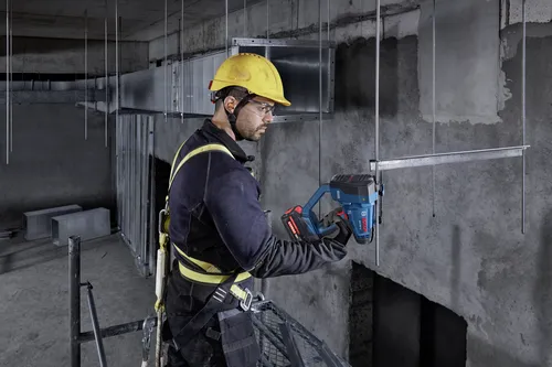 Bosch GGC18V-12 18V Brushless Threaded Rod Cutter used by a worker to cut metal rods in a concrete structure.