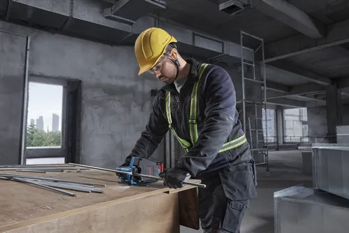 A worker using a Bosch GGC18V-12 18V Threaded Rod Cutter to cut metal rods on a work table at an interior commercial jobsite.