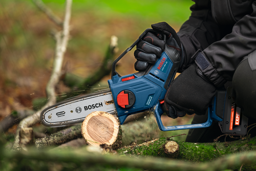The worker using the Bosch GKE18V-20 18V Pruning Saw for cutting a small log of wood.