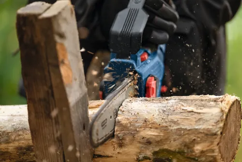 Close-up image of a worker using the Bosch GKE18V-20 18V Pruning Saw to cut through a log of wood.