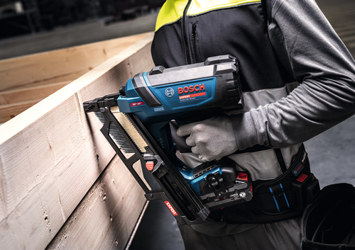 Image d’un ouvrier utilisant le cloueur de charpente Bosch EXNH18V-90MDN 18 V à angle de 30 degrés sur des planches en bois.