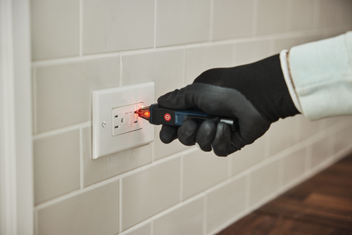Image d’un ouvrier utilisant le testeur de tension sans contact Bosch GVD1000-15 pour vérifier la tension d’une prise électrique.