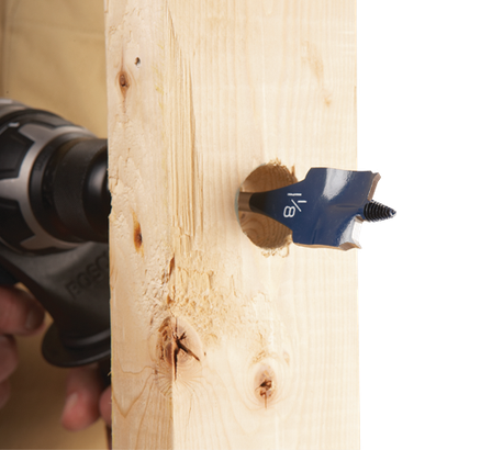 Mèche de perçage de 1/8" forant dans du bois. Une perceuse est visible en arrière-plan.