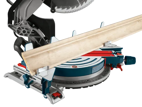 Bosch miter saw with blade guard, and wooden molding in position for cutting.