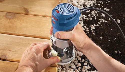 Bosch COLT 1.25 HP router, with operator using it to shape wood.