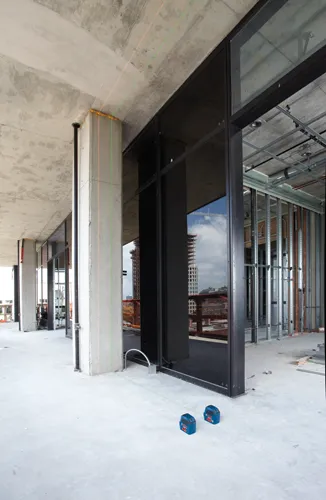 Bosch blue laser levels on a construction site, with concrete pillars and glass windows.