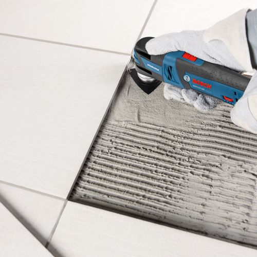 Bosch GOP12V-28 Starlock multi-tool cutting between tiles.