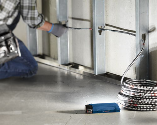 Person installing electrical conduit with a Bosch GLI12V-300 flashlight.