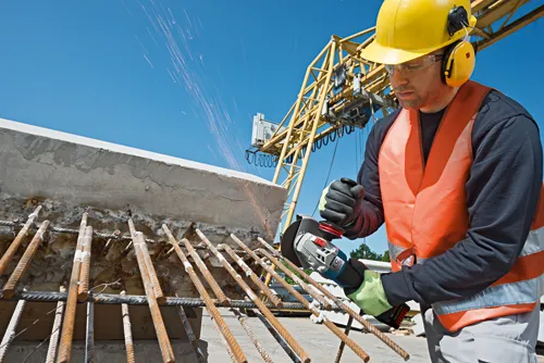 Bosch EC BRUSHLESS MOTOR angle grinder being used by a person in safety gear to cut rebar. Sparks are visible.