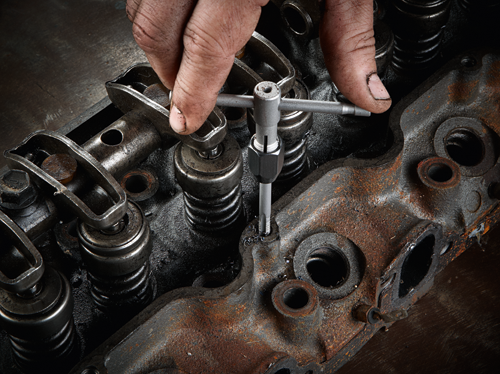 Hand using a tool on an engine head.