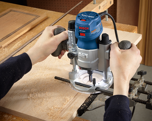Bosch GKF125CE Colt 1.25 HP router being used to cut a wood piece.