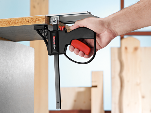 Bosch clamp with red handle clamping a wooden board.