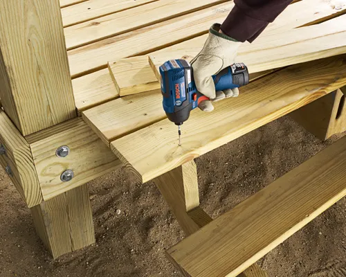 Bosch impact driver screwing into wooden plank.