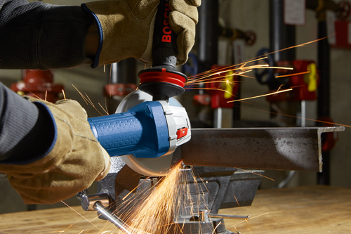 Bosch grinder cutting metal, producing sparks, held by gloved hands.