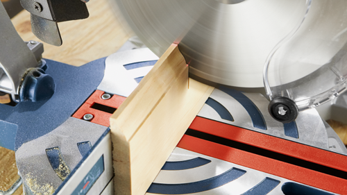 A miter saw cutting a wooden board.