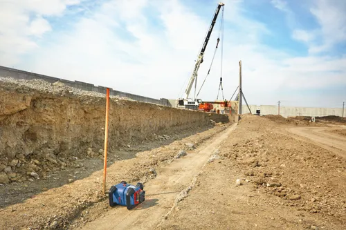 Construction site with a crane, a laser level, and a long wall.