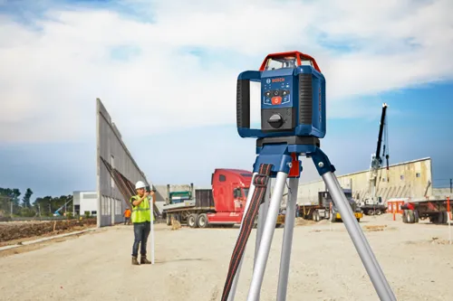 Bosch level mounted on tripod with a construction worker aiming at something in the distance.