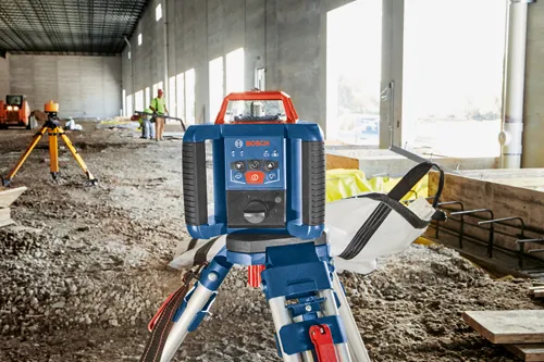 Bosch leveler with "BOSCH" logo, buttons, and tripod on a construction site.