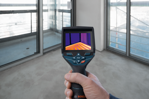 Bosch thermal imaging camera held by a person, displaying a thermal image of a room. "Func" and power buttons are visible.